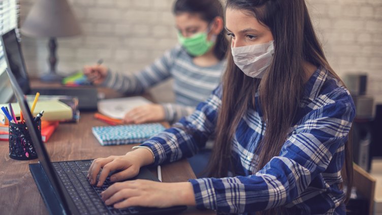 Young girls wearing protective face mask and studying at home quarantine due to the epidemic of Coronavirus COVID-19