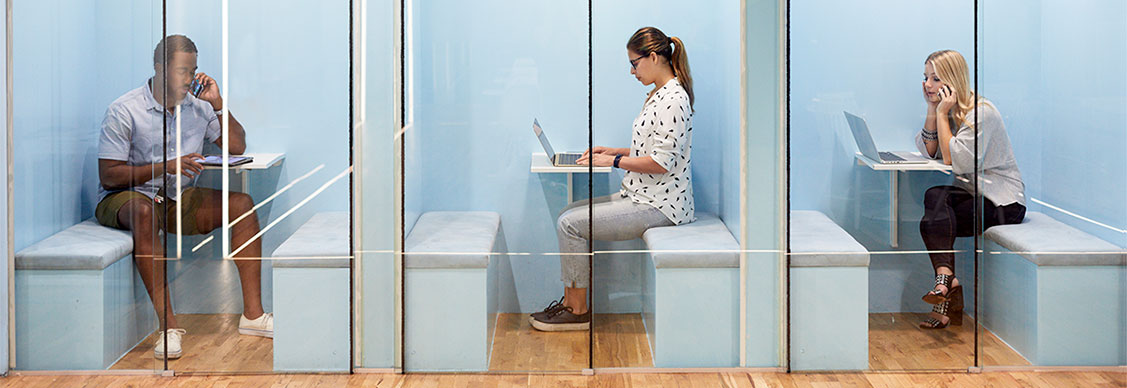 Multi-ethnic business people using laptops while sitting in cubicles at office