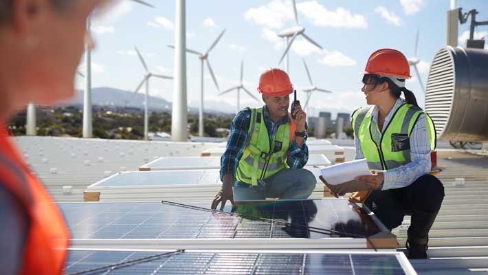 Engineers examining solar panels at alternative energy power plant 