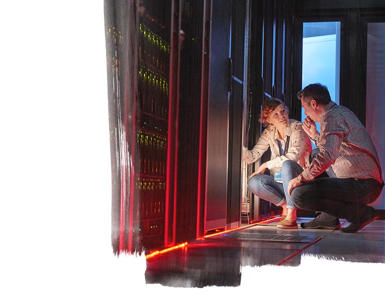 IT technicians talking at glowing panel in dark server room
