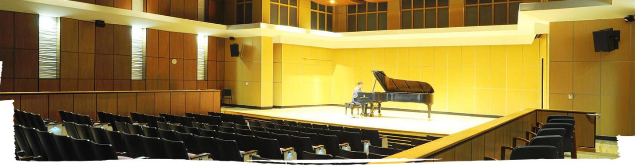 A student practising music on stage in an auditorium