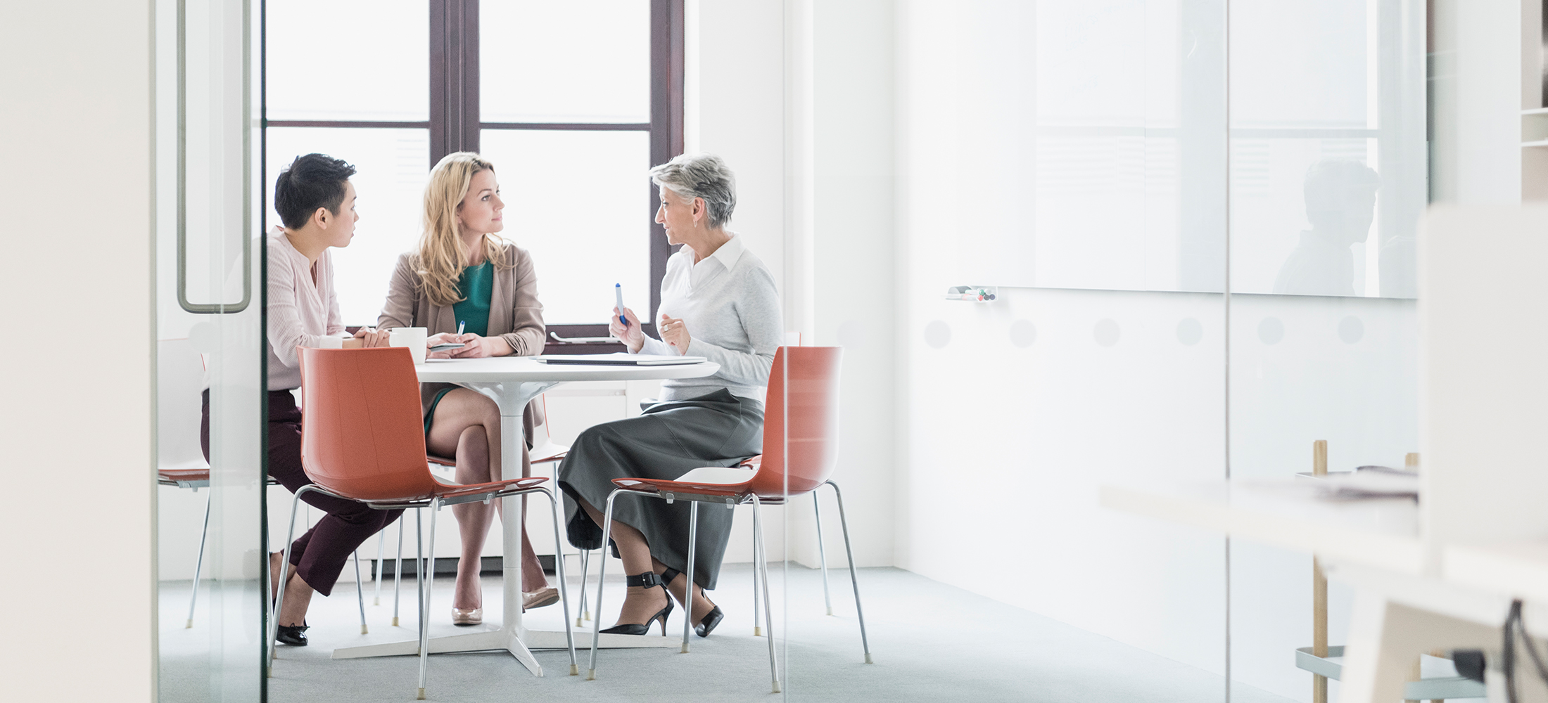 Three women sitting at table in modern office