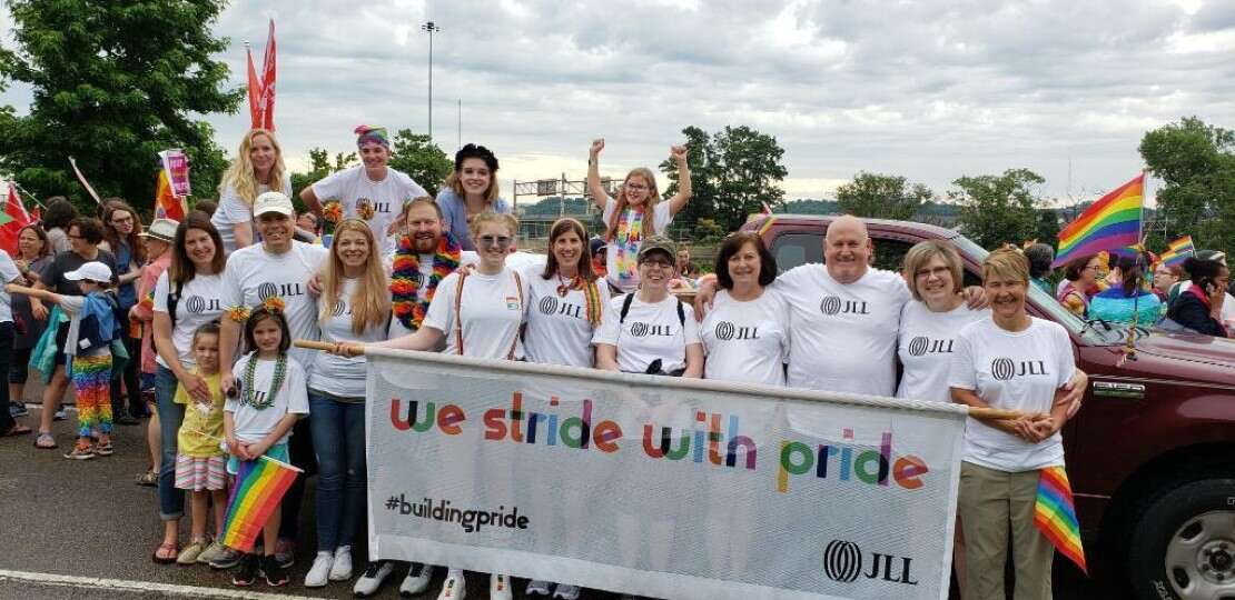 Group image of JLL employees holding a banner in a local pride parade