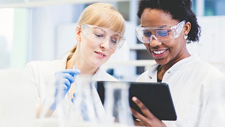 Lab assistants examining the test samples in laboratory with information on phone tablet