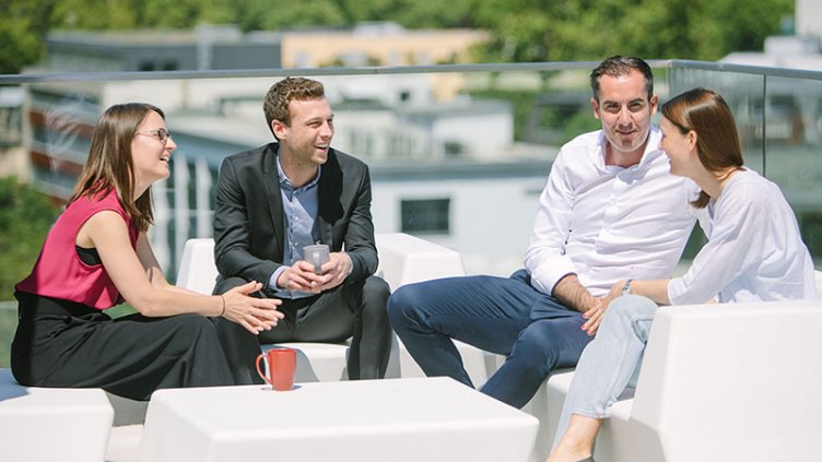 Four people having a conversation on an office roof deck